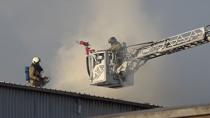 De brandweer blust de brand vanop het dak; Wiedauwkaai Gent.