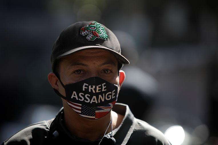 Een man met een mondkapje met de tekst 'bevrijd Assange'. Beeld REUTERS