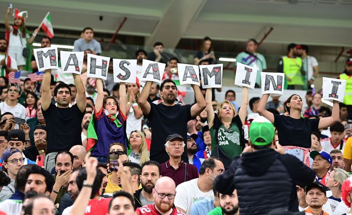 Iraniërs houden borden omhoog tijdens de match tegen de VS waarop de naam van de vermoorde jonge Koerdische vrouw Mahsa Amini staat te lezen.