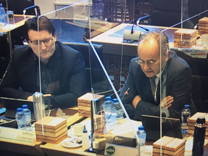 Beschermd door kuchschermen voert Frank Kuijpers (CDA) het woord over de Zanddijk. Naast hem zijn partijgenoot Jeffrey Oudeman