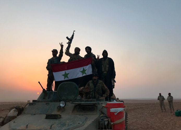 Militairen van het Syrische regeringsleger dragen de Syrische vlag na het heroveren van de grensplaats Albu Kamal op Islamitische Staat.