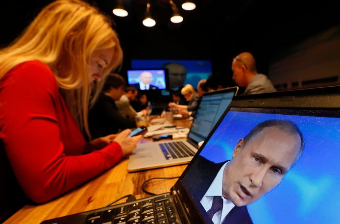 Russische journalisten kijken naar de tv-uitzending van een toespraak van president Poetin.