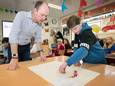 Een leerling van groep 8 van basisschool De Burchtgaarde in Breda geeft uitleg aan wethouder Daan Quaars bij de zelfgemaakte plattegrond van de verkeerssituatie in de Rijnauwenstraat.
