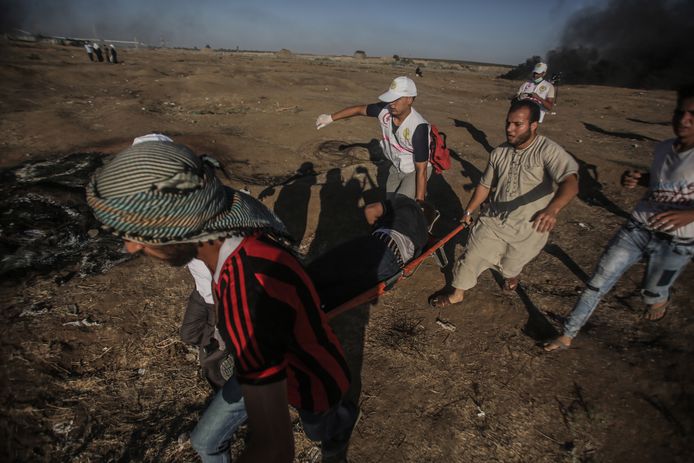 Palestijnse demonstranten dragen een gewonde man weg na een confrontatie met Israëlische troepen aan de grenszone tussen de Gazastrook en Israël.