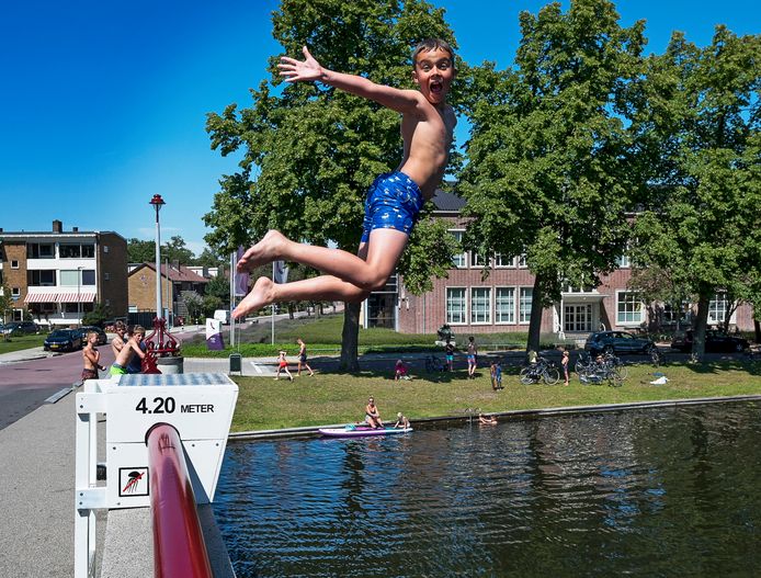 Jeugdige zwemmers vermaken zich op de Parijse brug in Woerden waar een illegale springschans is geplaatst.