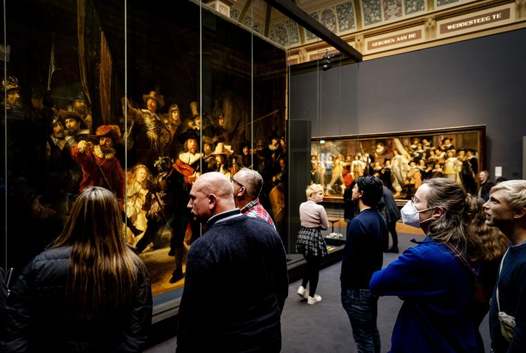 Bezoekers bekijken de achterzijde van schilderij De Nachtwacht in het Rijksmuseum. De onderzoekers in het museum gaan de achterkant van het enorme schilderij bestuderen. Beeld ANP