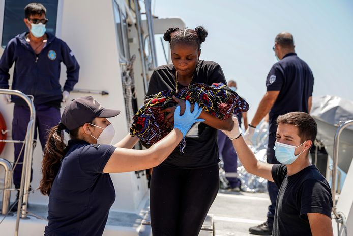 Illustratiebeeld: een vluchtelinge aan boord van een schip van de Griekse kustwacht draagt een pasgeboren baby in haar armen terwijl ze voet aan wal zet op het Griekse eiland Lesbos.