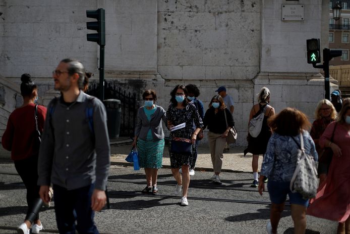 Mensen met mondmaskers steken de straat over in Lissabon.