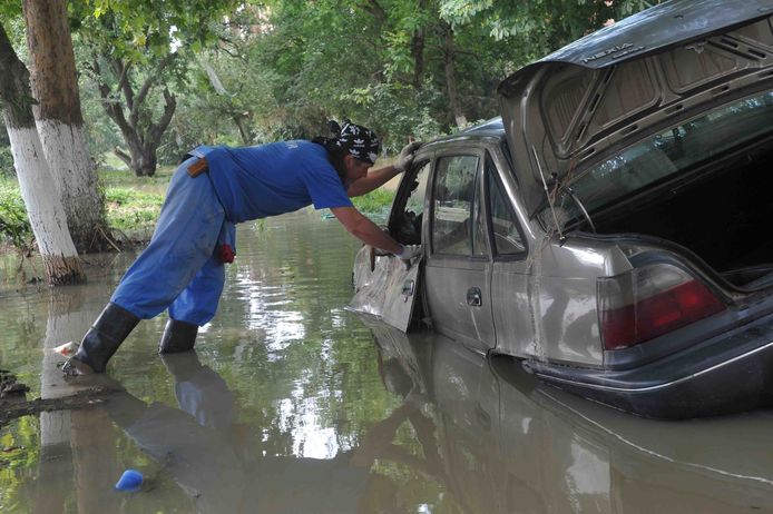 Een reddingswerker onderzoekt een gezonken auto na overstromingen in de Russische stad Kranodar in juli 2012. Bij hevige overstromingen kwamen toen zeker 171 mensen om het leven, tienduizenden mensen verloren al hun bezittingen.