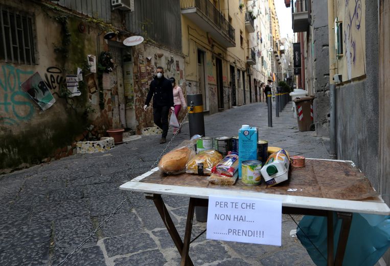 Een ‘Tavolo solidare’ – ‘solidariteitstafel’ – in Napels. Op het briefje staat ‘Voor wie niet kan kopen... neem.’ Beeld AFP