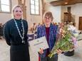 Henny van Os glundert met een bos bloemen, een oorkonde en de Veerse waarderingsonderscheiding op de revers van haar jasje. Burgemeester Frederiek Schouwenaar speldde de bijzondere onderscheiding op.