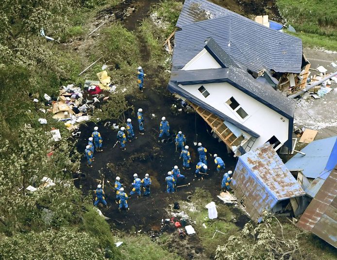 De politie zoekt naar overlevenden bij een huis dat zwaar beschadigd en verplaatst is door de aardbeving.