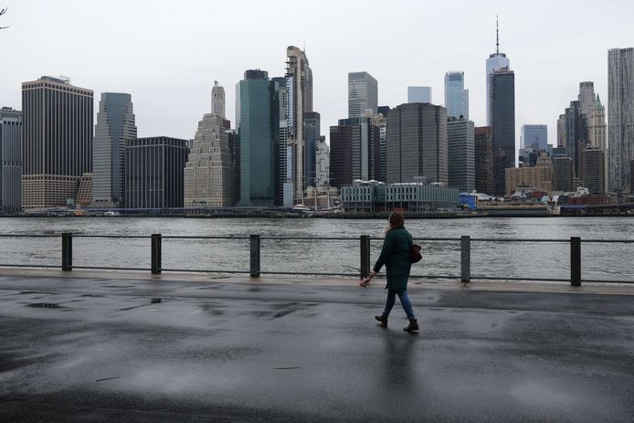 Een eenzame wandelaar in Brooklyn, New York, met de wolkenkrabbers van Manhattan op de achtergrond.