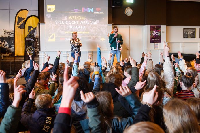 Wethouder Marianne de Bie en influencer Thomas van Grinsven ontvangen de scholieren in het NAC-stadion voor de aftrap van de Week van het Geld.