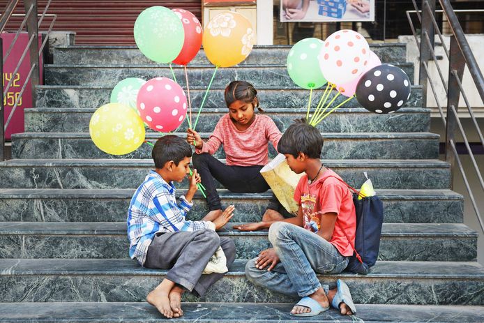 Indiase kinderen spelen op een trap in Amritsar met hun verdiende geld, terwijl ze wachten op nieuwe klanten voor de ballonnen die zij verkopen. Foto Narinder Nanu