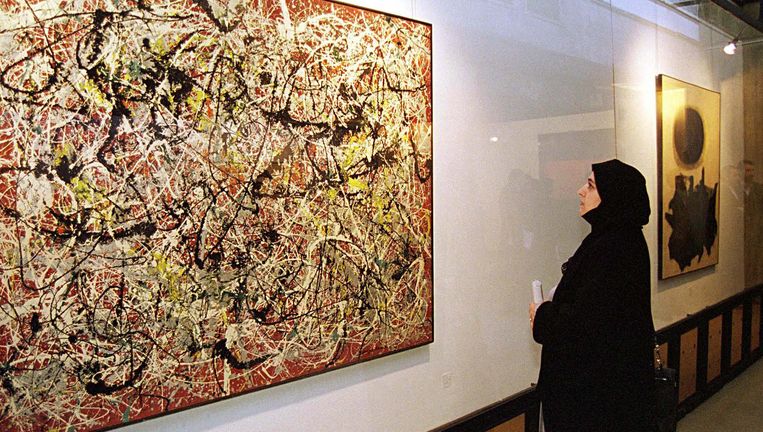 Een vrouw bekijkt een werk van de Amerikaanse schilder Jackson Pollock in Teheran. Beeld getty
