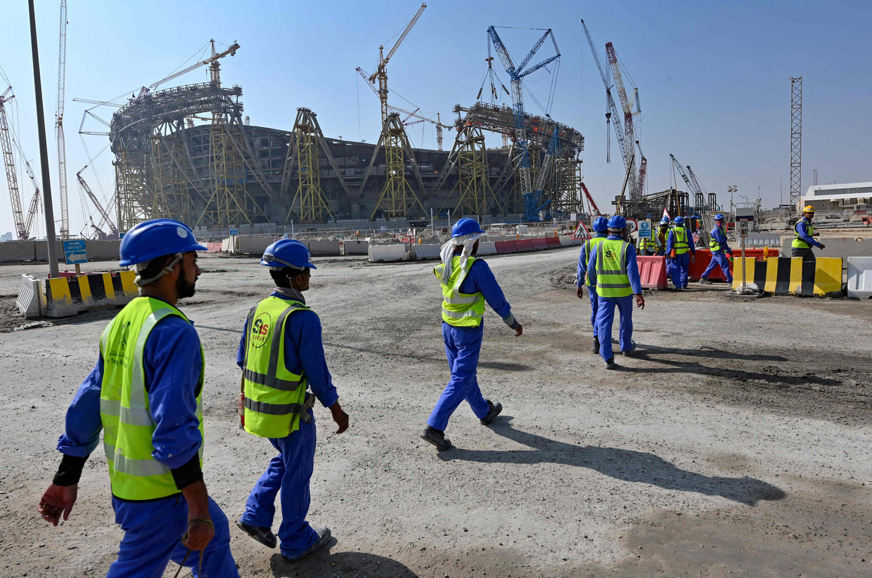 Bouwvakkers bij het Lusailstadion in Qatar, een van de nieuwe stadions voor het WK voetbal in 2022. Duizenden arbeidsmigranten werken onder erbarmelijke omstandigheden aan de bouw.  Beeld AFP