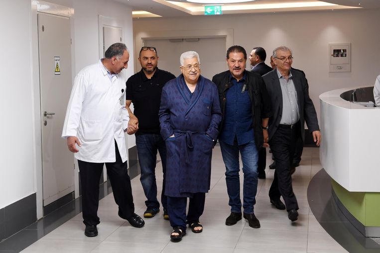 De Palestijnse president Mahmoud Abbas (midden, met kamerjas aan) maakt een wandelingetje door de gang van het ziekenhuis.  Beeld REUTERS