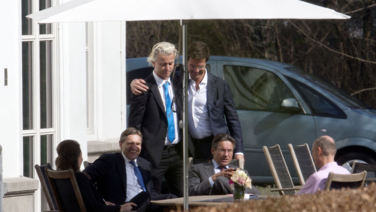 Rutte met zijn arm om PVV-leider Wilders, in aanwezigheid van CDA-leider Verhagen (zittend), en Kamerleden Buma (CDA), Agema (PVV) en Blok (VVD) op een van de dagen van onderhandelingen in het Catshuis. Beeld anp