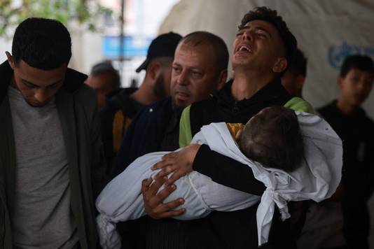 Een man huilt met een omgekomen kind in zijn armen. 