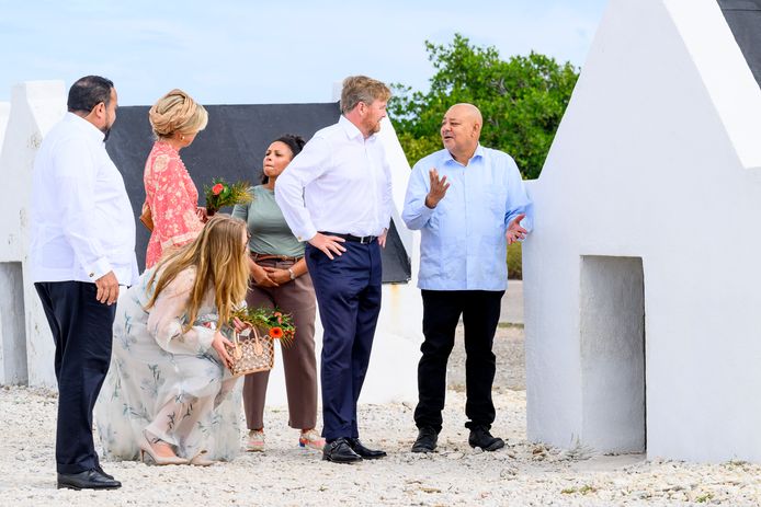 Prinses Amalia bekijkt een slavenhutje van binnen, terwijl haar vader koning Willem-Alexander met schrijver en rondleider Bòi Antoin praat.