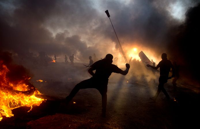 Tussen brandende autobanden en terwijl Israëlische troepen reageren met traangas, gooien de demonstranten stenen naar de Israëlische soldaten.