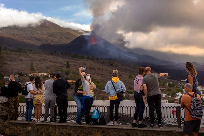 Toeristen maken selfies met de smeulende vulkaan op de achtergrond.