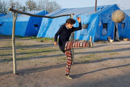Een meisje speelt voetbal in een vluchtelingenkamp vlakbij Marioepol.