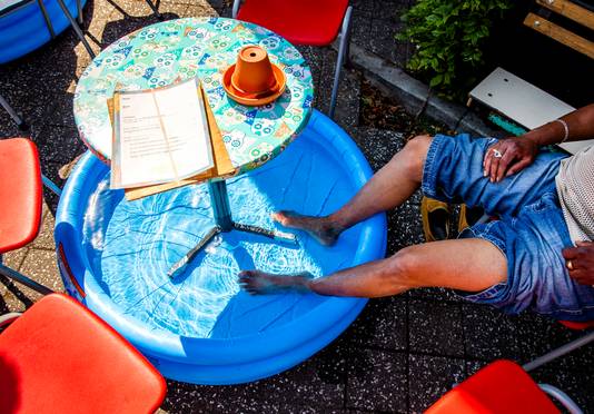Een man zit met zijn voeten in een zwembadje op een terras in Amsterdam.