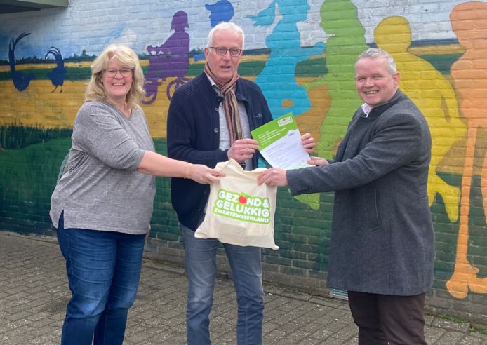 Hannie Kubbenga en Harry Drenthe van obs de Vogelaar ontvangen uit handen van wethouder Jan van der Poel (rechts) een pakket met menstruatieproducten.