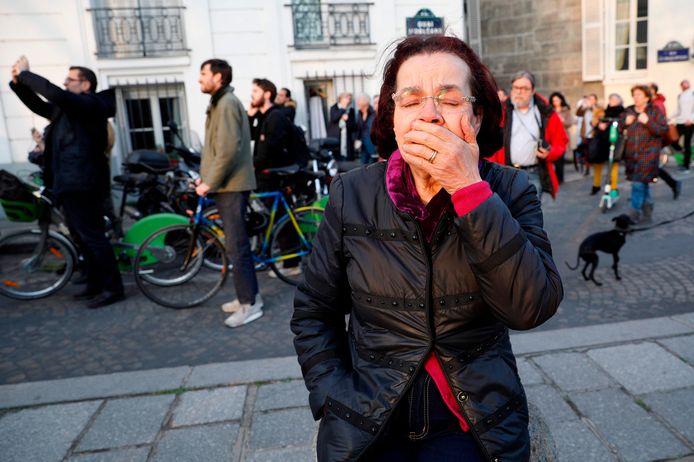 Een vrouw kijkt toe hoe de vlammen uit de Notre-Dame slaan