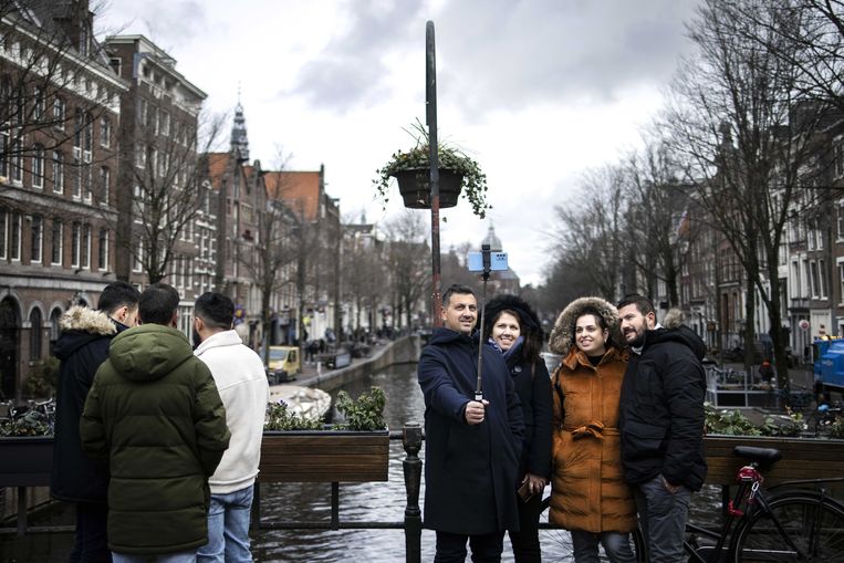 Toeristen maken een selfie bij de Oudezijds Voorburgwal in Amsterdam.  Beeld ANP