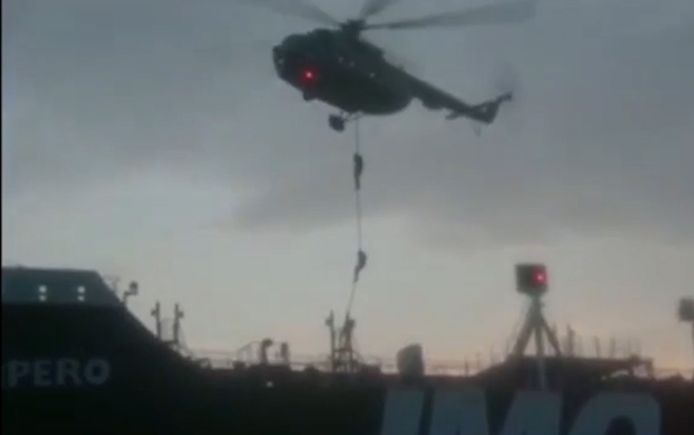 Leden van de garde laten zich uit een helikopter op het schip zakken.