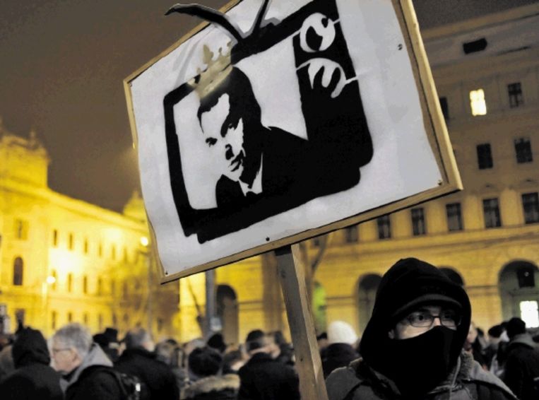 Hongaren in protest tegen de nieuwe mediawet. Op het protestbord wordt premier Viktor OrbÃ¡n afgebeeld als de koning van de televisie. ( FOTO AP ) Beeld AP