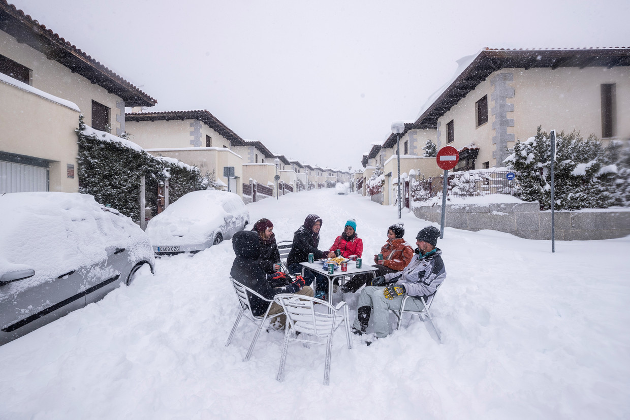 Buren doen een drankje in de sneeuw in een buitenwijk van Madrid.  Beeld AP