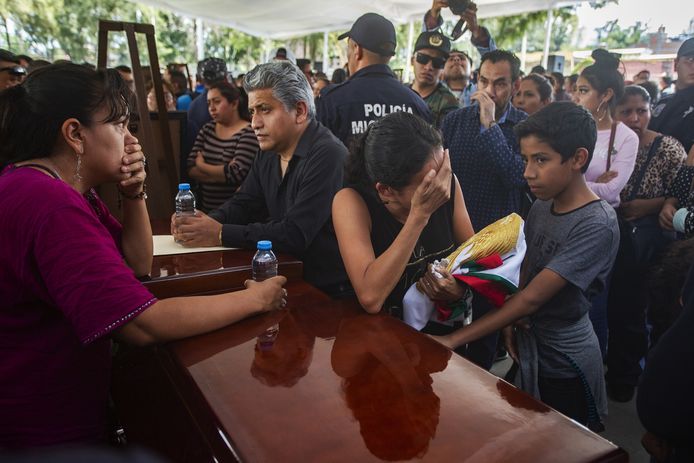 Nabestaanden treuren bij de kisten van dertien politieagenten die afgelopen maandag gedood werden bij een hinderlaag in Aguililla.