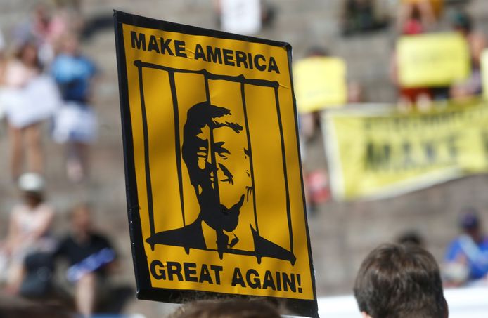 Een protestbord dat Trump in een gevangeniscel afbeeldt samen met zijn fameuze leuze "Make America Great Again!"