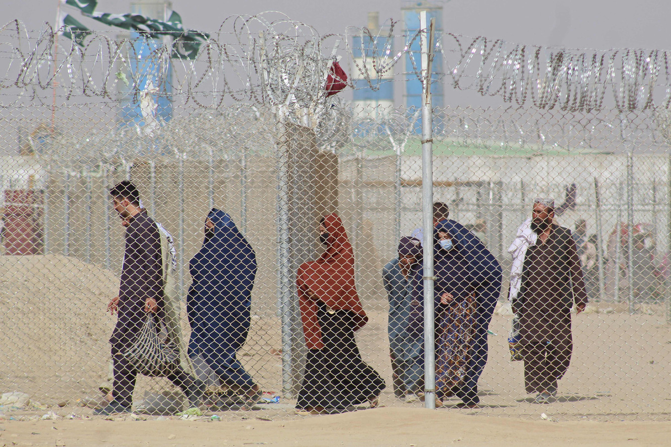 Afghanen lopen voorbij een hek met prikkeldraad. Er dreigt een humanitaire crisis.