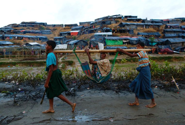 Rohingya-jongeren dragen een oudere vrouw in de buurt van het vluchtelingenkamp bij Cox's Bazar. Beeld REUTERS