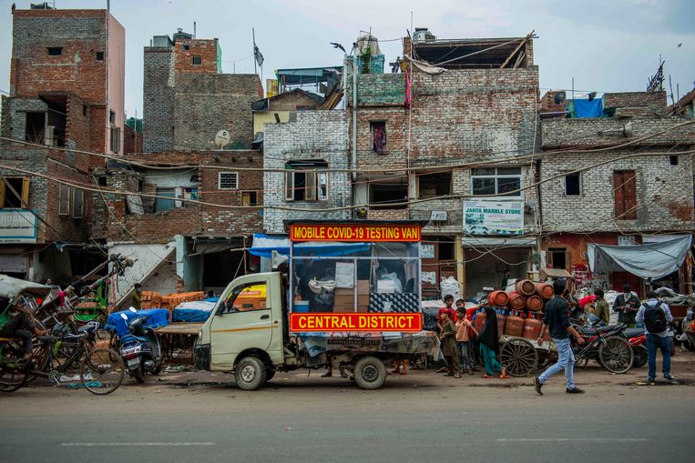 Een mobiel laboratorium voor het testen op Covid-19 staat geparkeerd in een sloppenwijk in de Indiase miljoenenhoofdstad Delhi.  Beeld Hollandse Hoogte / Zuma Press