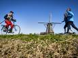 Een man fietst langs de molens in Kinderdijk tijdens een zonnig lenteweekend in 2022.