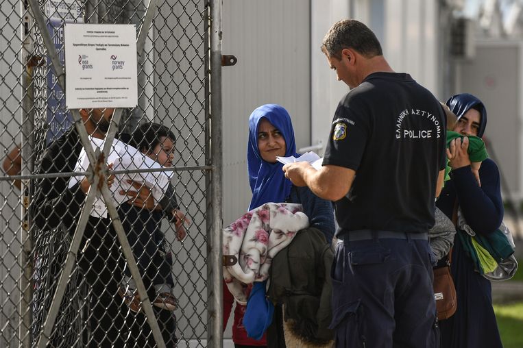 Vluchtelingen tonen hun papieren aan een politieagent bij een asielzoekerscentrum in het Griekse Fylakion Beeld AFP