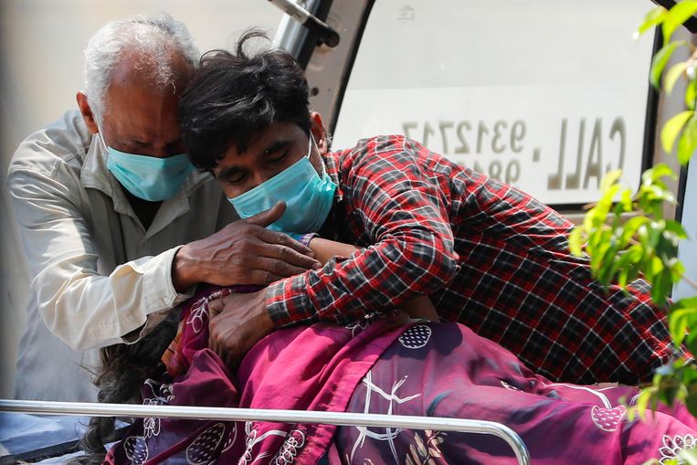 Familieleden van een Indiase vrouw die aan Covid-19 is overleden rouwen bij het ziekenhuis in New Delhi. Beeld REUTERS