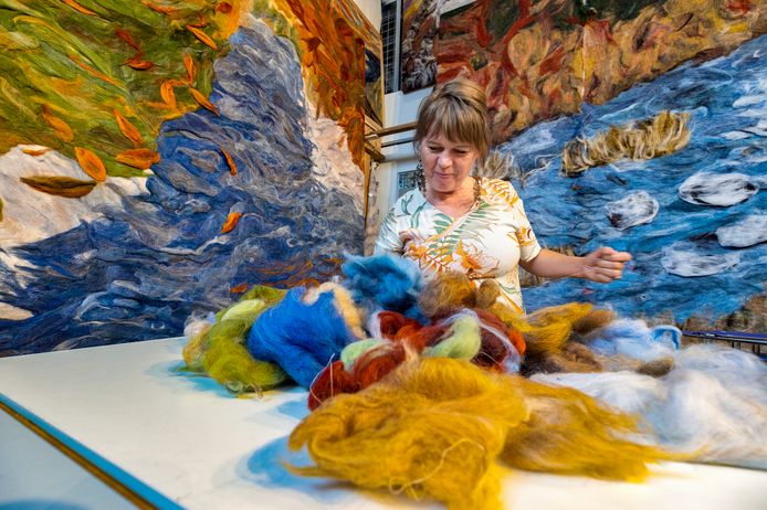 Marian Verdonk, met achter haar hangen de immens grote wol-kleden die de kunstenares maakt.