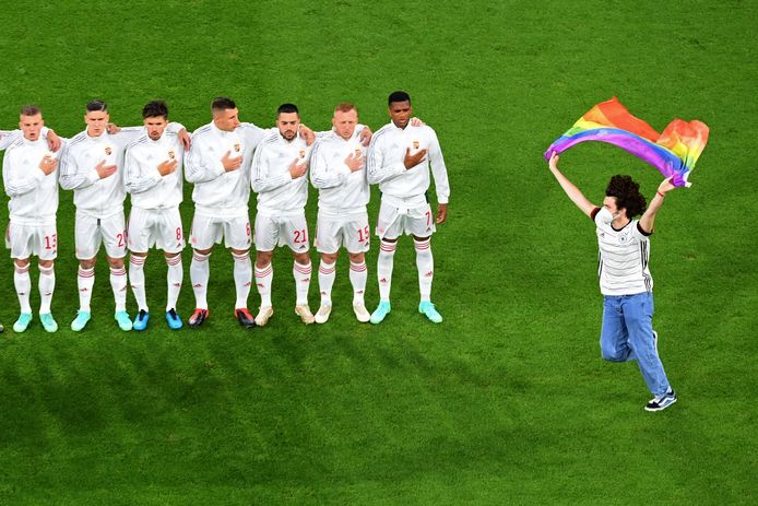 TOPSHOT - A person waving the rainbow flag runs on the pitch as the Hungary players line up for the national anthems the UEFA EURO 2020 Group F football match between Germany and Hungary at the Allianz Arena in Munich on June 23, 2021. (Photo by Matthias Hangst / POOL / AFP)