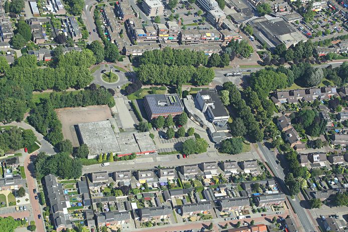 Foto van het gebied waar de woongebouwen moeten komen. In het midden van de foto onder de rotonde van links naar rechts: kantoor van PostNL, muziekschool, Rabobank. Veldhoven
