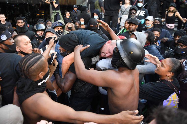 Een belaagde tegendemon­strant wordt door een aan­hanger van Black Lives Matter bevrijd uit de boze menigte. Beeld AFP