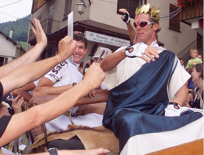 Il magistrale velocista italiano Mario Cipollini saluta la folla mentre arriva su un pontone vestito da Caesar per celebrare la sua quarta vittoria consecutiva al Tour de France 86 e il compleanno di Caesar nel 2099 (1999).