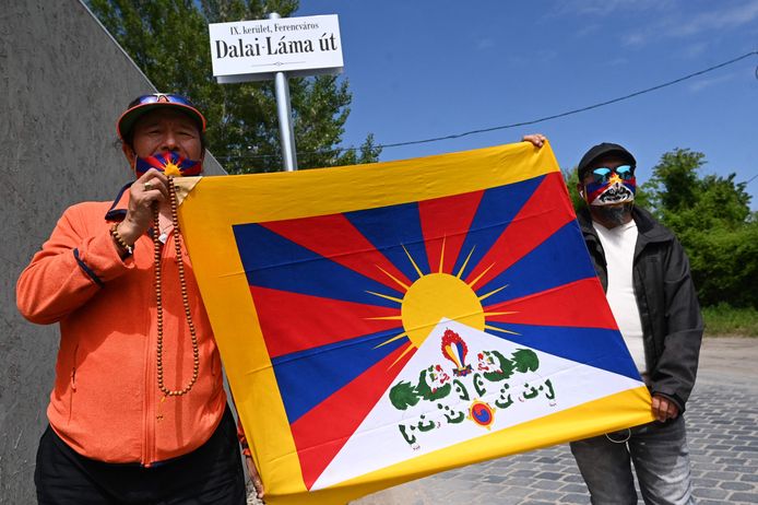 Mensen houden een Tibetaanse vlag vast onder het bord van de Dalai Lamastraat.