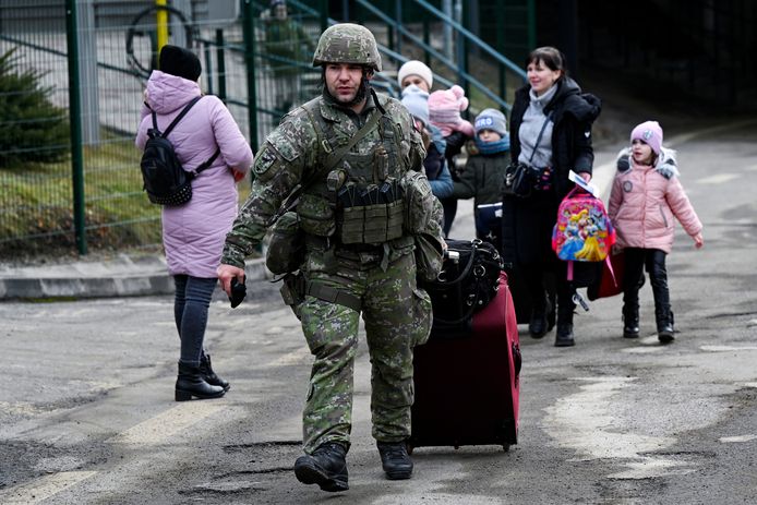 Een Slovaakse soldaat helpt enkele vluchtelingen met hun bagage.